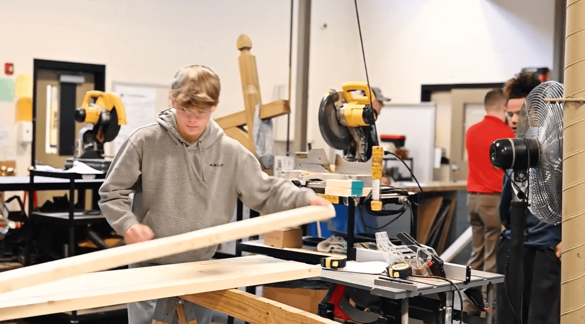 male student measuring 2x4 wood in workshop class